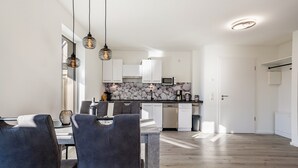 Een moderne keuken met witte kasten, een betegelde spatwand en hanglampen.