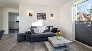 Een moderne woonkamer met een grijze bank, een salontafel en een schilderij aan de muur.