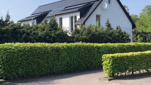 Een huis met zonnepanelen, een schotelantenne en een keurig onderhouden haag.
