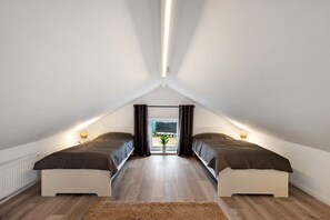 A bedroom with two beds, a radiator, a potted plant, and a view through a window. - Holiday Home 'Küsten-Bude' with Private Terrace, Garden, and Wi-Fi (Elmenhorst)