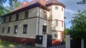 Un bâtiment à deux étages, doté d’un toit recouvert de tuiles rouges, de nombreuses fenêtres et d’une entrée fermée par un portail.