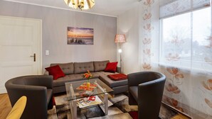 Un salon comprenant un canapé, deux fauteuils, une table basse et un lustre.