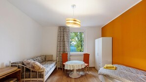 Une pièce de taille modeste comprenant un lit, un canapé, une petite table et une fenêtre.