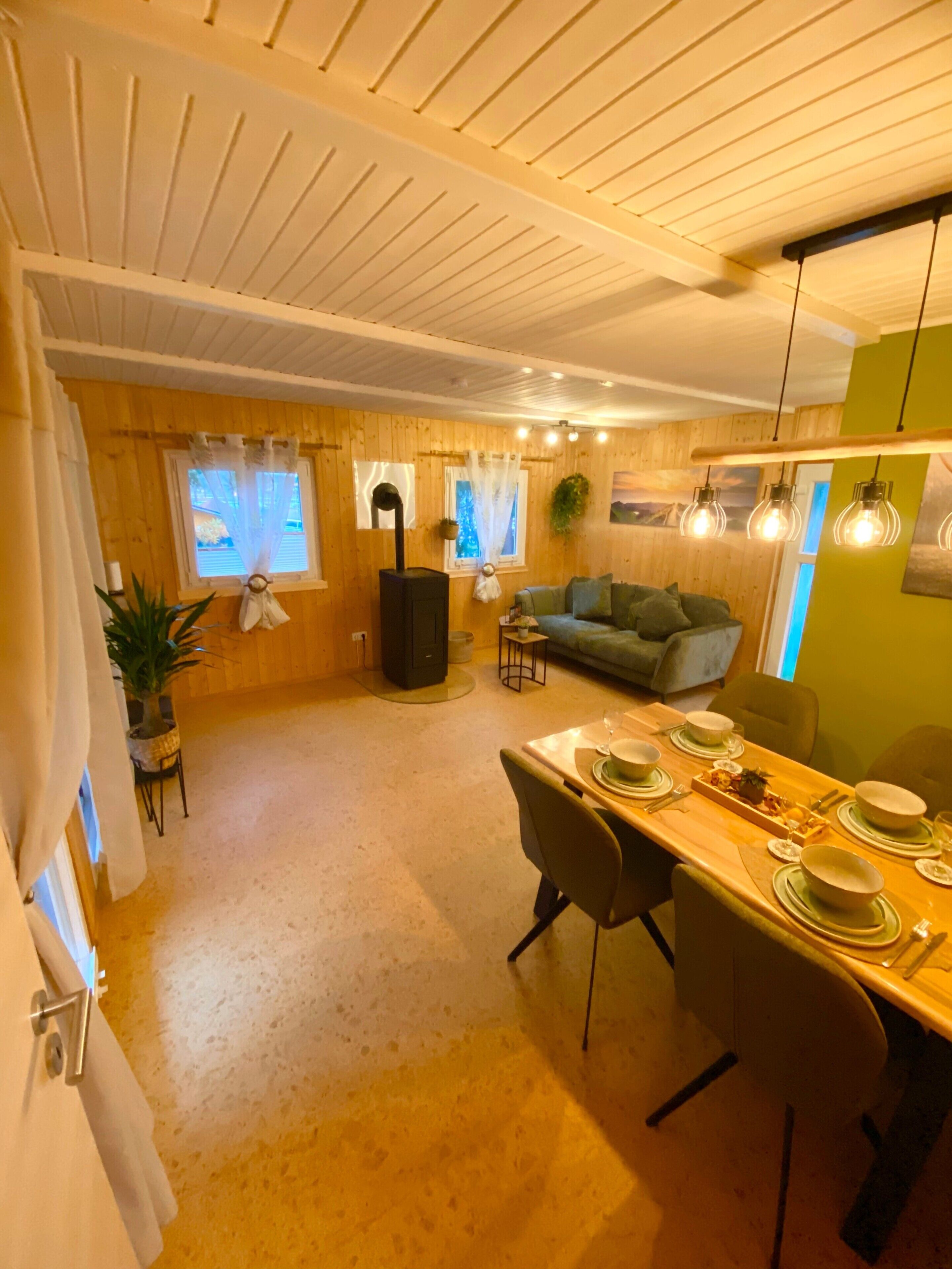 A cozy room with a dining table set for four, a sofa, a fireplace, and a window with curtains.
