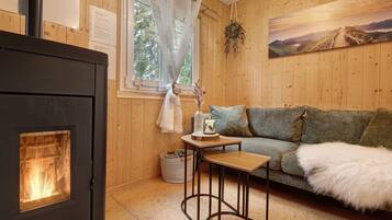 A cozy room with a wood-burning stove, a sofa, a small table, and a painting on the wall.