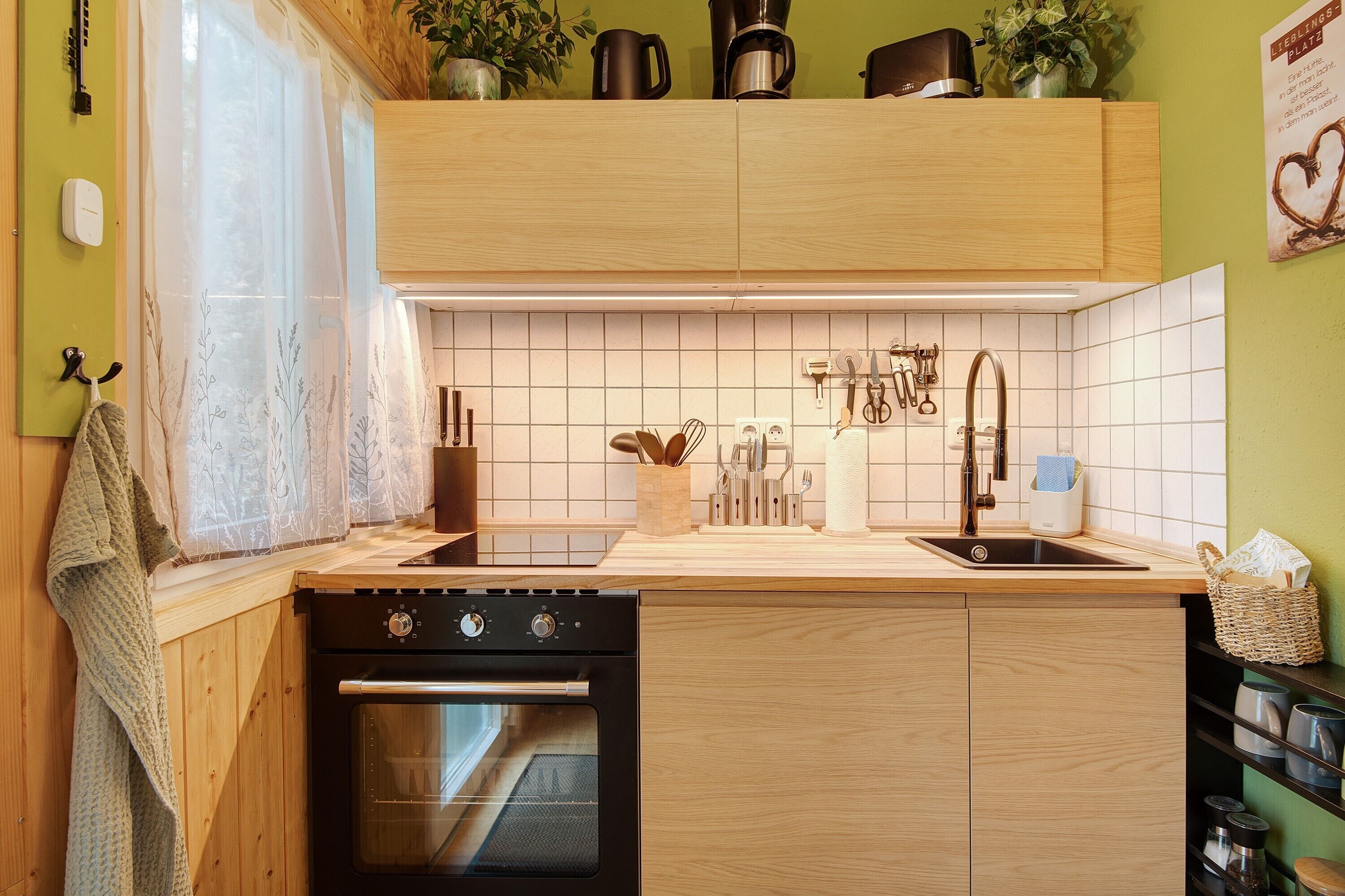 A kitchen with wooden cabinets, a built-in oven, a sink, and various kitchen utensils.