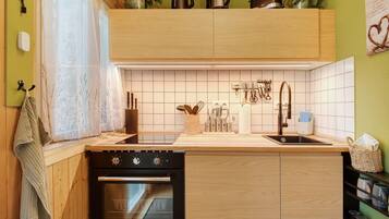 A kitchen with wooden cabinets, a built-in oven, a sink, and various kitchen utensils.