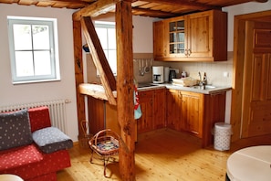 Een gezellige keuken met houten kasten, een zithoek met een rode bank en een raam dat zorgt voor natuurlijk licht.