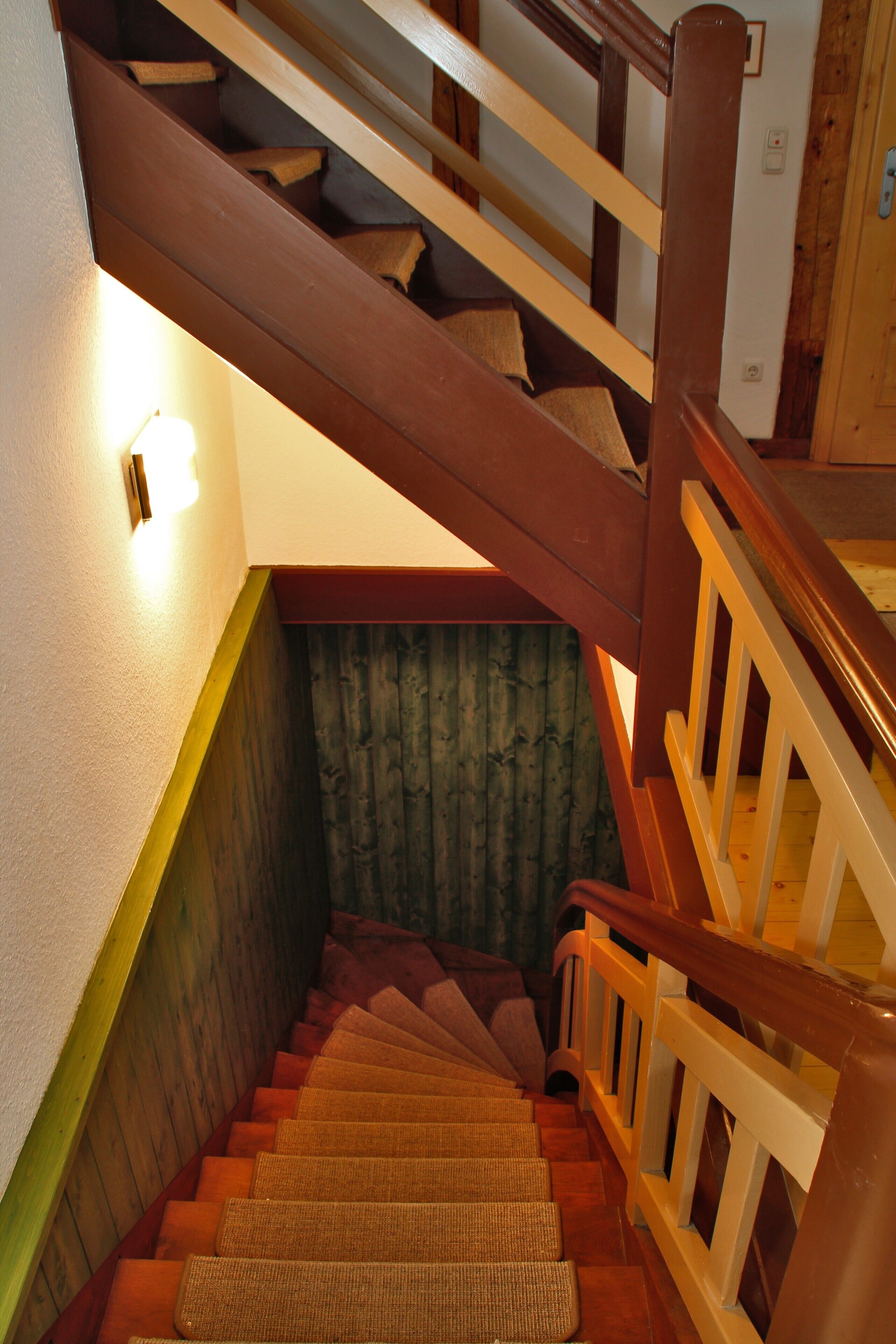 Una escalera de madera con barandilla y un aplique en la pared.