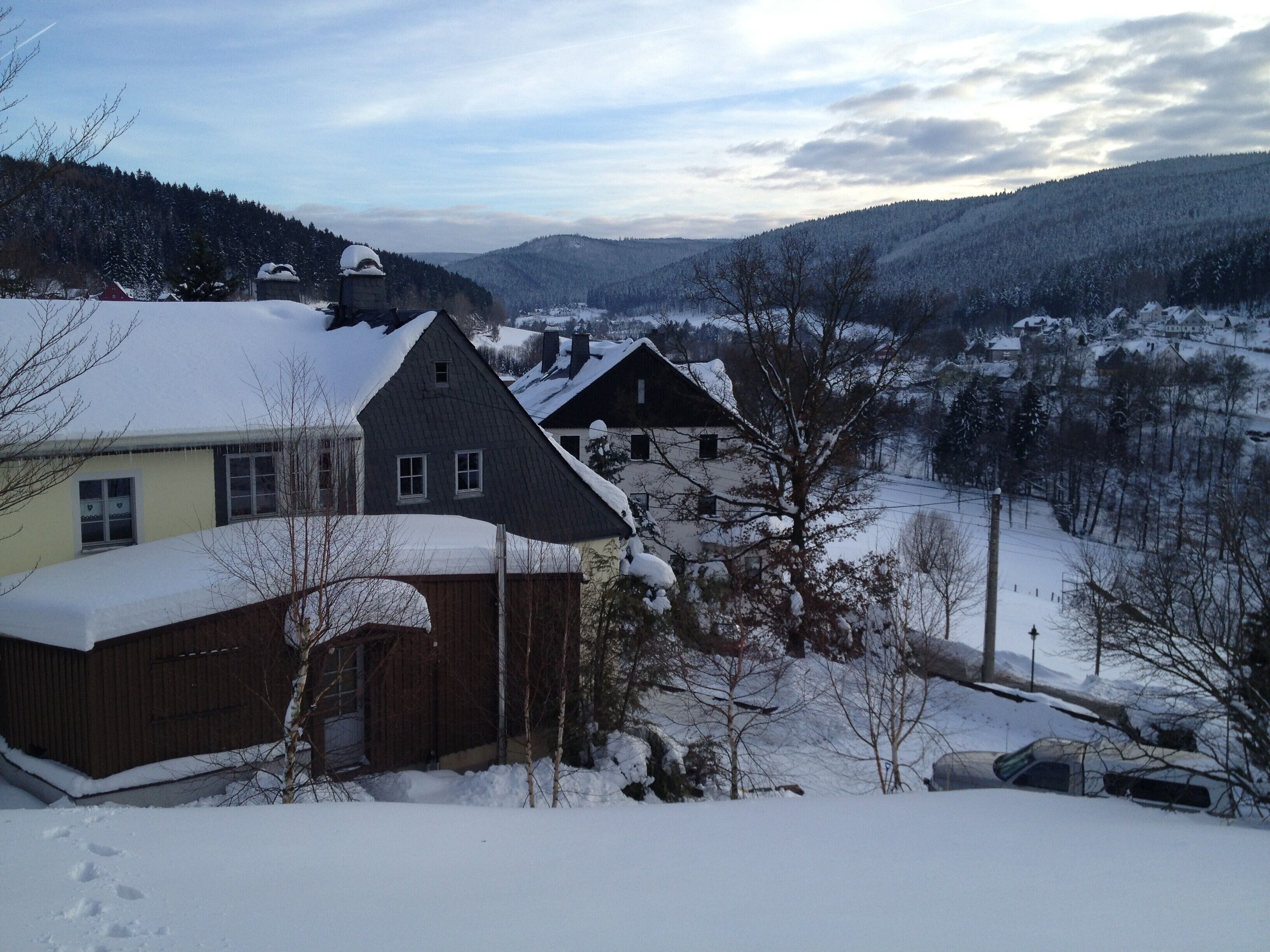 Un pueblo rural con casas cubiertas de nieve y montañas al fondo.