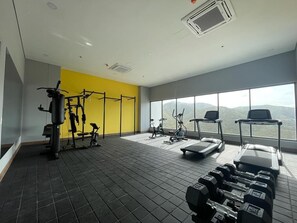 Stay fit and active with a range of exercise equipment, including dumbbells, a bench press, treadmill, and stationary bike, all set against a backdrop of a serene outdoor view.