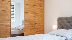 Un dormitorio con una cama, un armario de madera, una mesita de noche y una lámpara de pared.