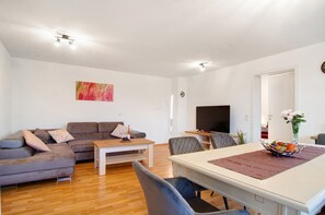 Uma sala de estar moderna com um sofá, mesa de jantar e televisão.