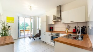 Una cocina moderna con armarios blancos, encimera de madera y horno empotrado.