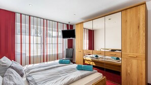 Une chambre d’hôtel avec deux lits, une télévision, un miroir et une armoire.