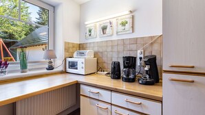 Une cuisine équipée d’un four à micro-ondes, d’une machine à café et d’une fenêtre donnant sur les arbres.