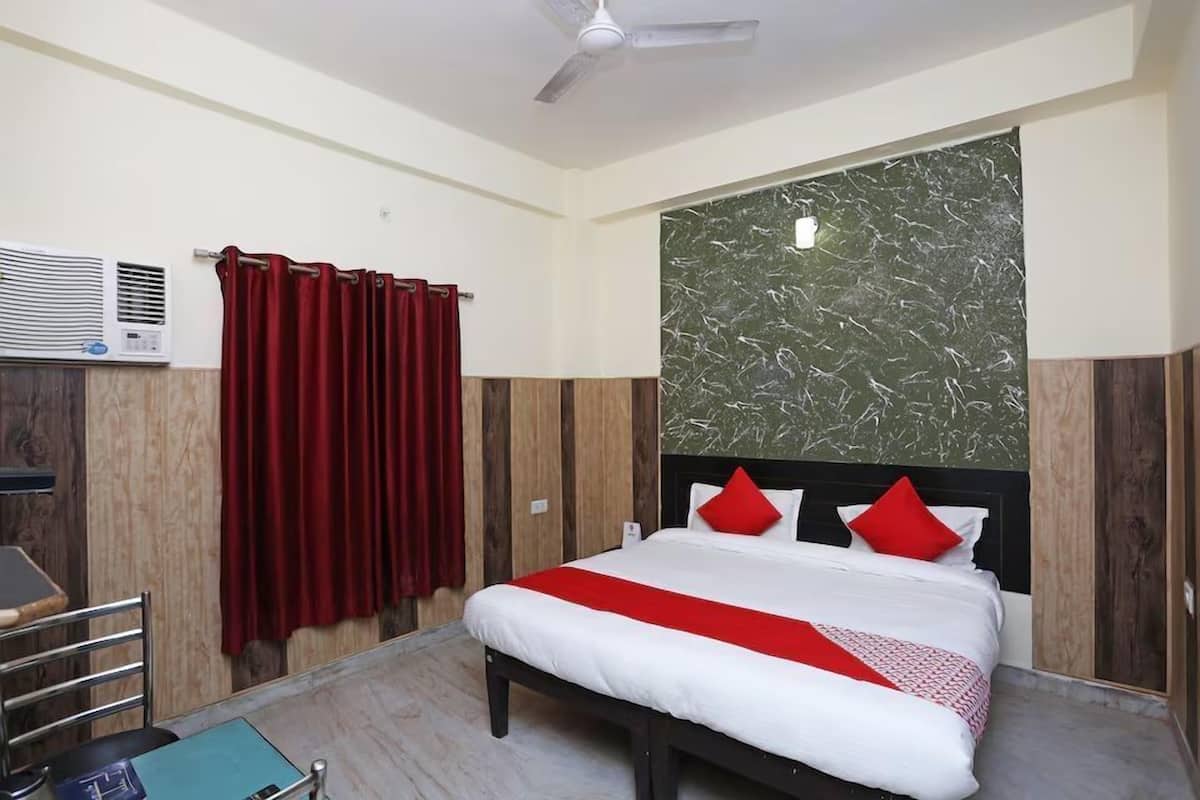 A hotel room with a bed, a ceiling fan, a red curtain, and a marble-patterned wall.