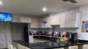 Een moderne keuken met een centraal eiland, barkrukken, houten vloeren en een plafondventilator.