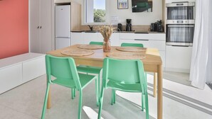 Une cuisine moderne avec des meubles blancs, une table en bois et deux chaises vertes.