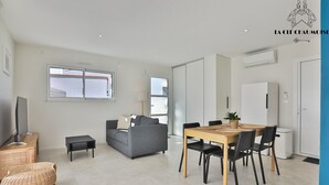 Una sala de estar moderna con un sofá, televisor, mesa de comedor, sillas y una mesita auxiliar.