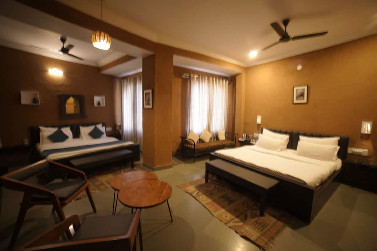 A hotel room with a bed, a sofa, a small table, a chair, and a ceiling fan.