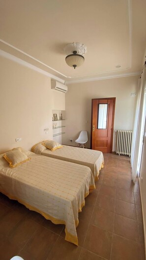 A bedroom with two beds, a chair, a radiator, and a door. - Complete, Spacious House, With Pool and Surrounded by Nature (Alzira)