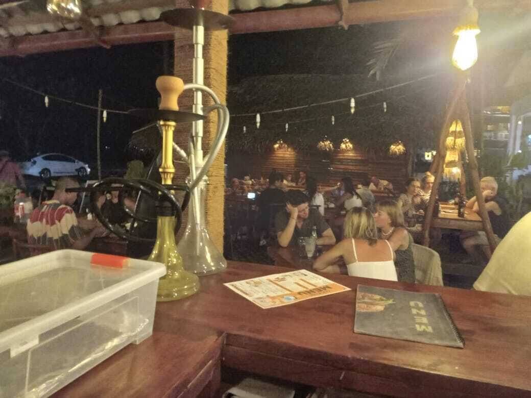 A bar area with a hookah, a menu, and a plastic container on the counter.
