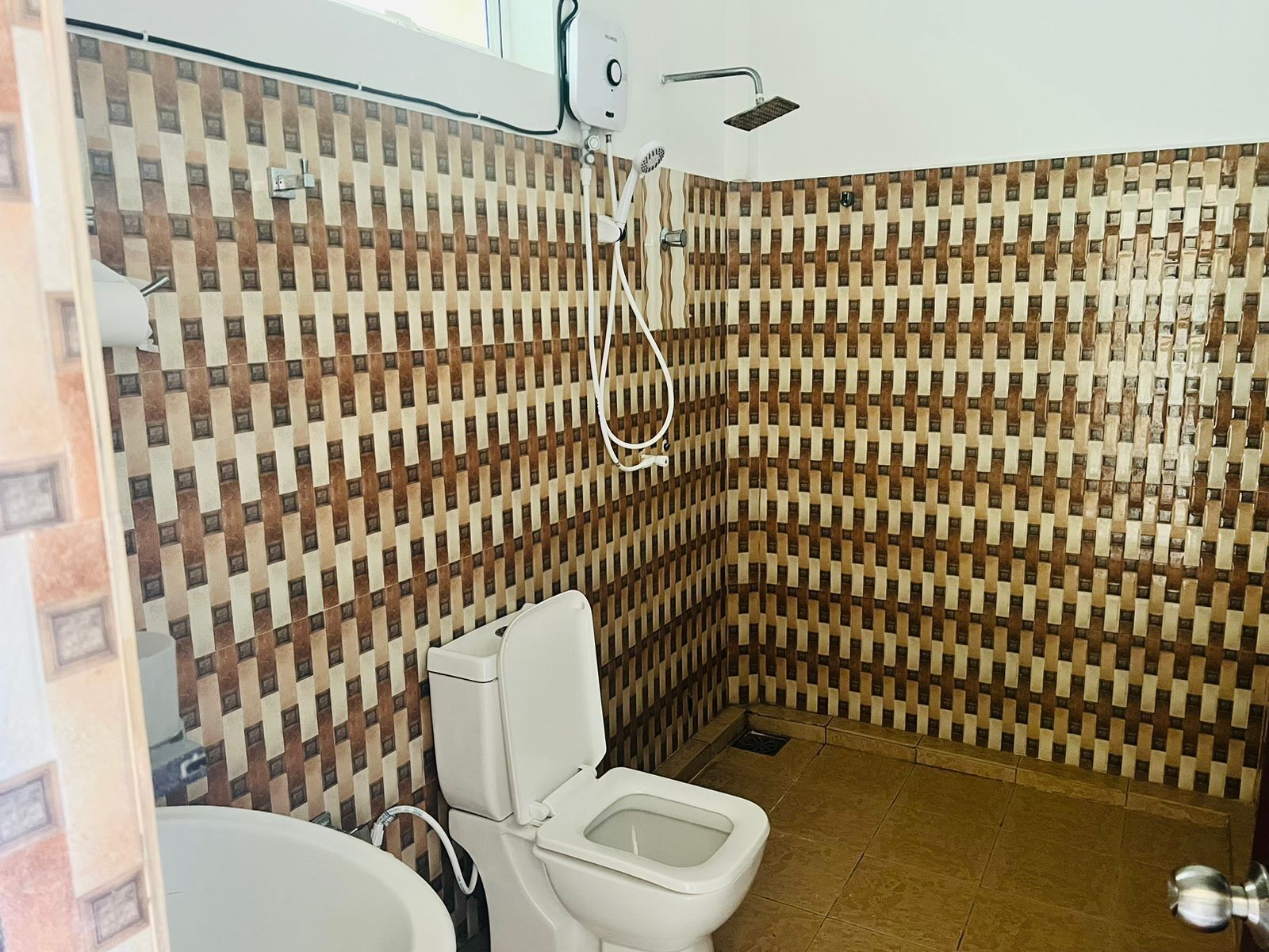 A bathroom with a patterned tile wall, a toilet, and a shower.