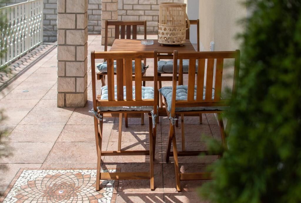 An outdoor patio with a wooden table and chairs, a woven basket, and a tiled floor.