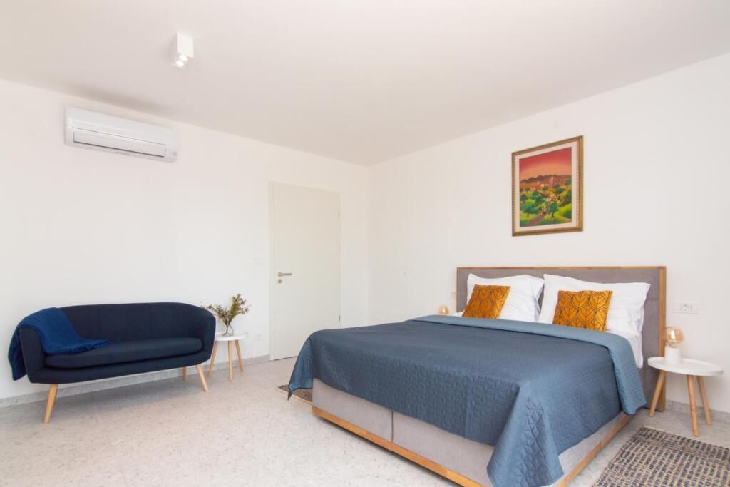 A bedroom with a bed, a sofa, a small table, and a painting on the wall.