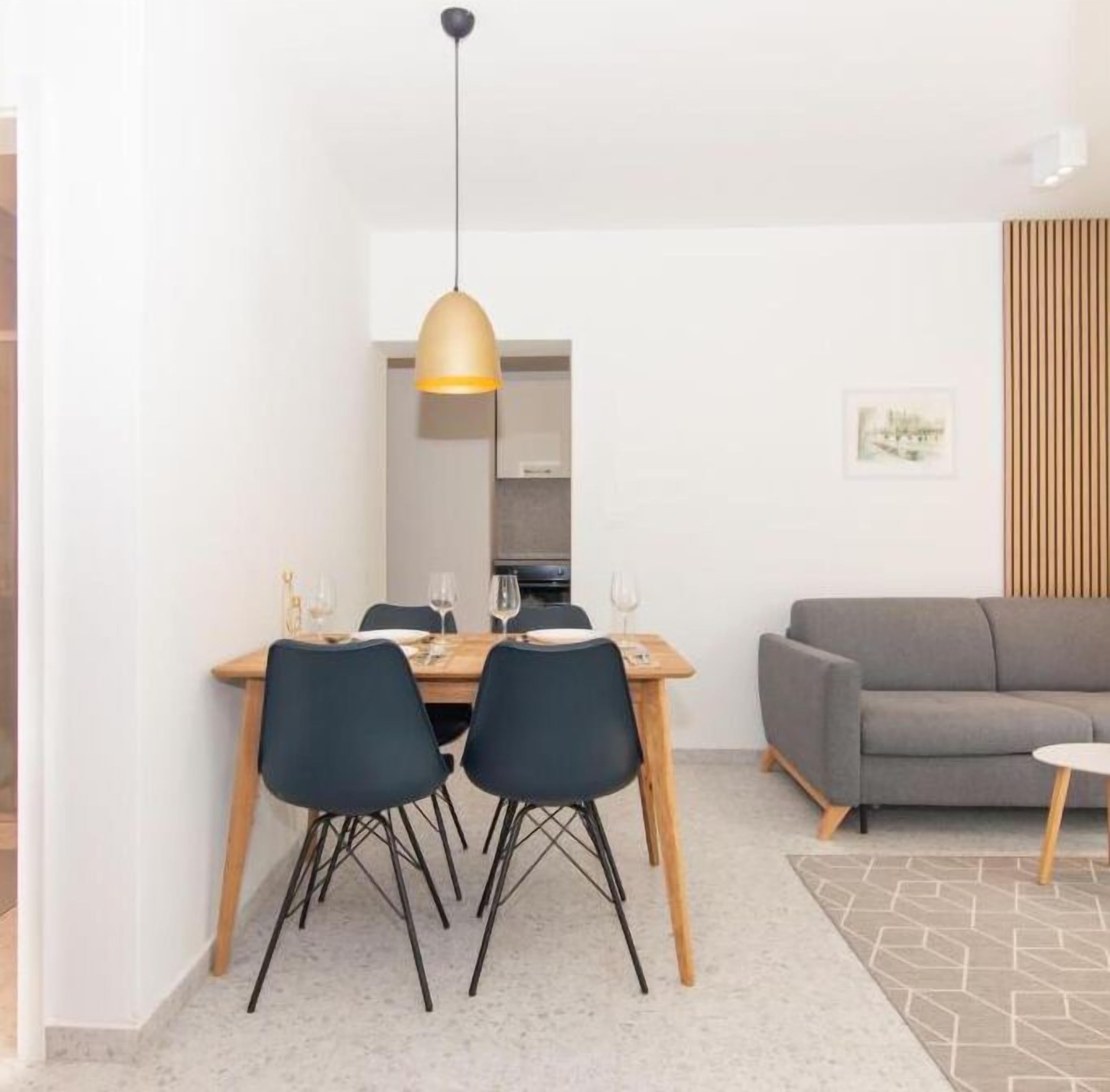 A modern dining area with a wooden table, black chairs, and a pendant light.