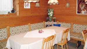 Un comedor con paneles de madera, un banco estampado con motivos florales y una mesa cubierta con mantel blanco.