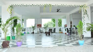A spacious indoor area with a checkered floor, several potted plants, and a seating arrangement.