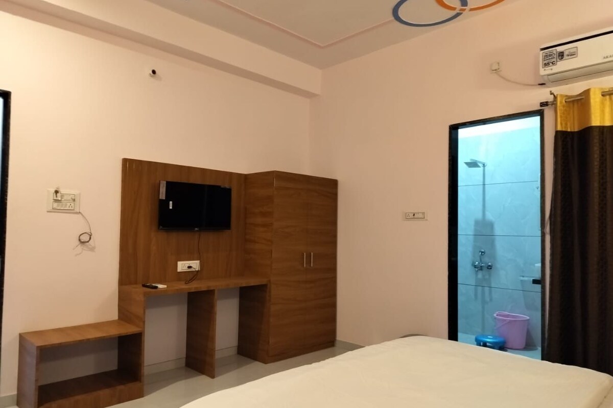 Une chambre à coucher comprenant un lit, une armoire en bois, un téléviseur et un espace douche.