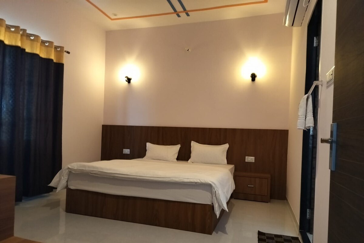 Une chambre à coucher avec une tête de lit en bois, deux tables de chevet, un lit avec une literie blanche et deux lampes fixées au mur.
