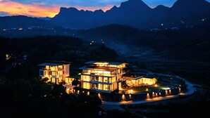 A modern multi-story building with large windows and a well-lit exterior. - XMAN Sunrise Peaks Resort (Zhangjiajie)