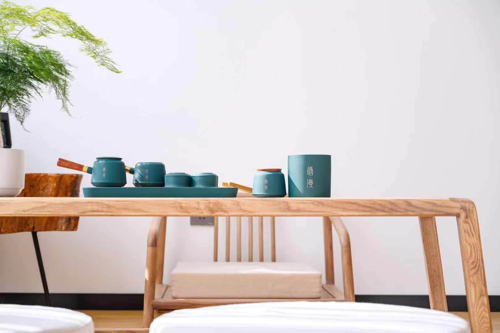 A wooden table with teal ceramic tea sets and a white vase.