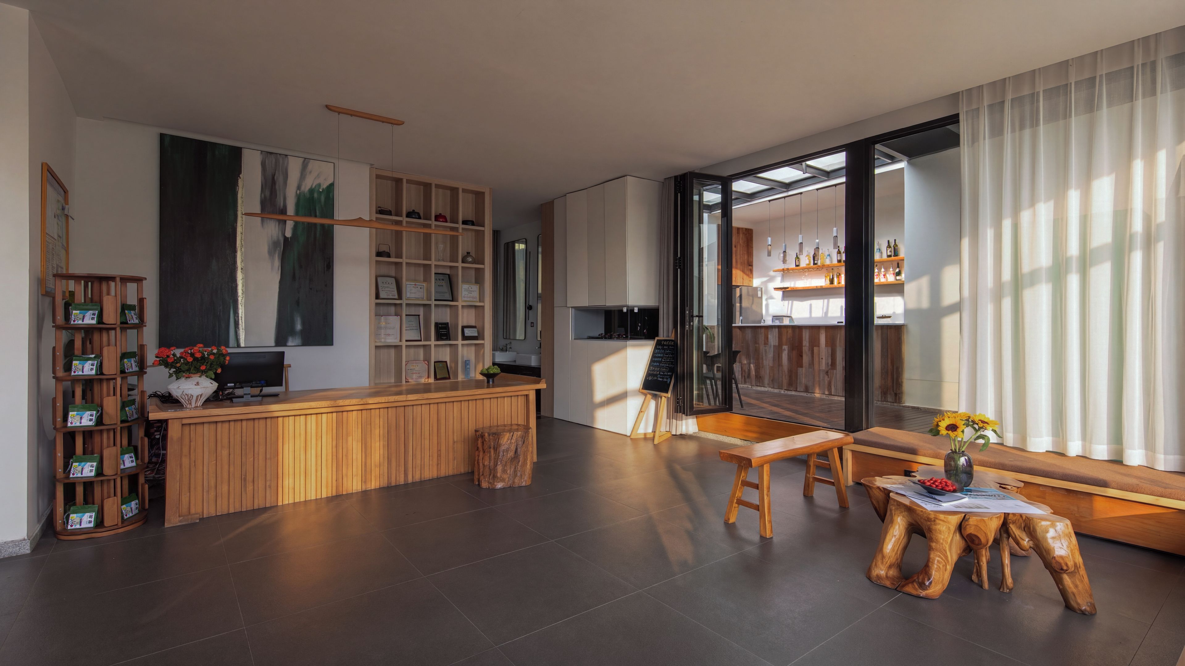 A modern interior with a wooden reception desk, a large abstract painting, and a bar area with bottles.