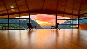A spacious room with a wooden floor and large windows offering a mountain view. - XMAN Sunrise Peaks Resort (Zhangjiajie)