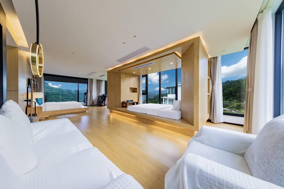 Une chambre d’hôtel moderne avec deux lits, une grande fenêtre et une vue sur l’extérieur.
