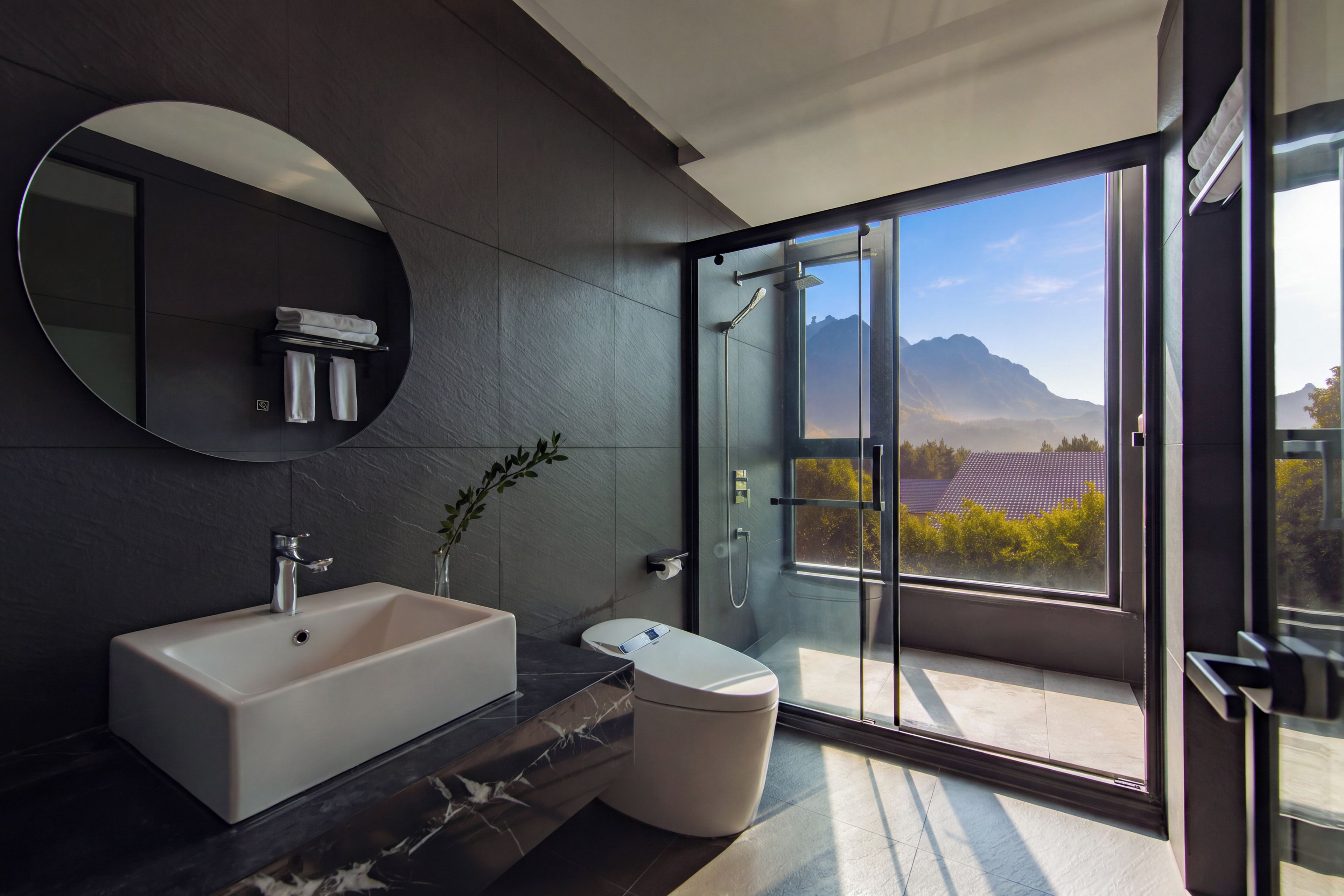 Un bagno moderno con uno specchio grande, una vasca e un water. Si vede una finestra con vista sulle montagne.