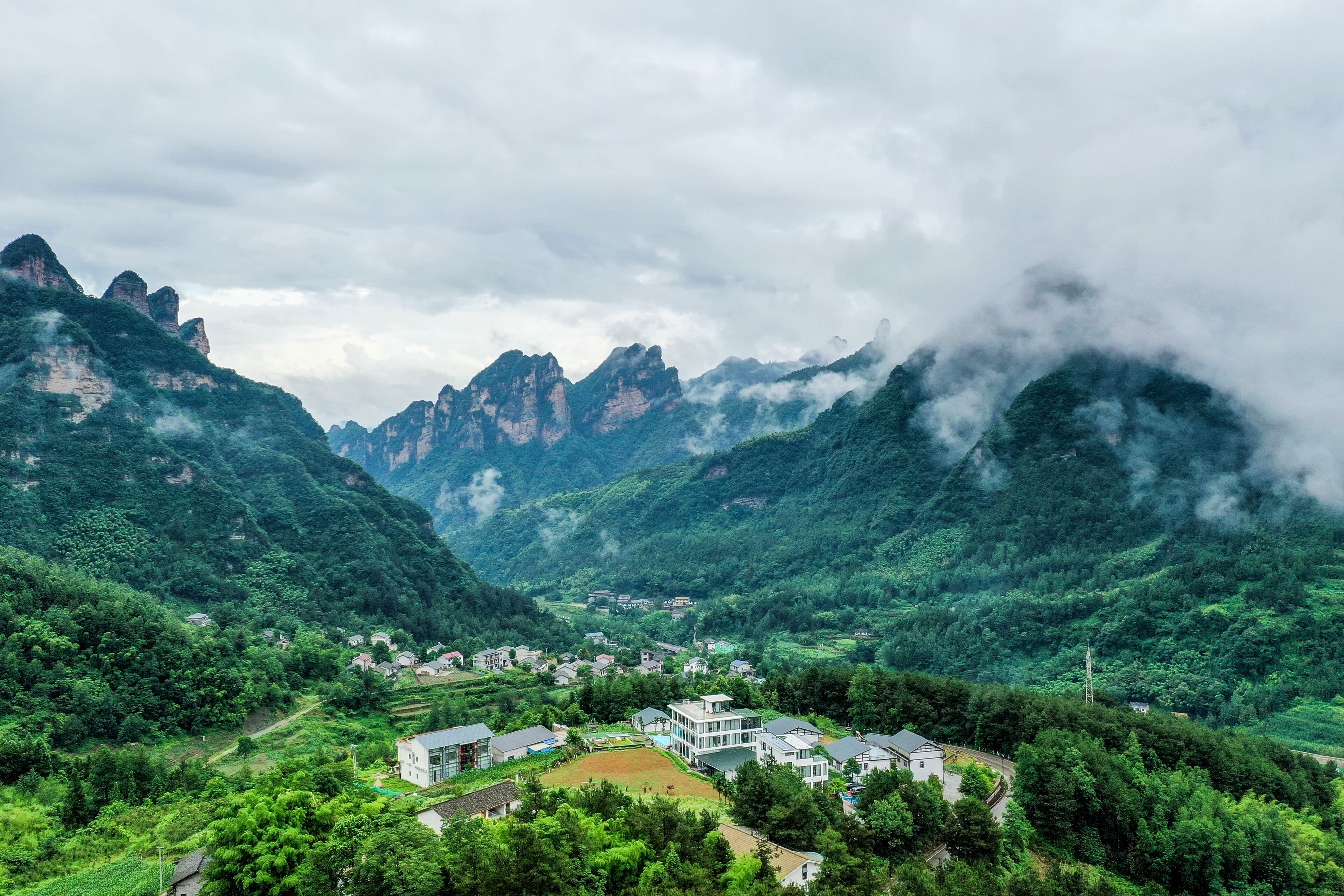 A mountainous landscape with a valley and a small cluster of buildings.