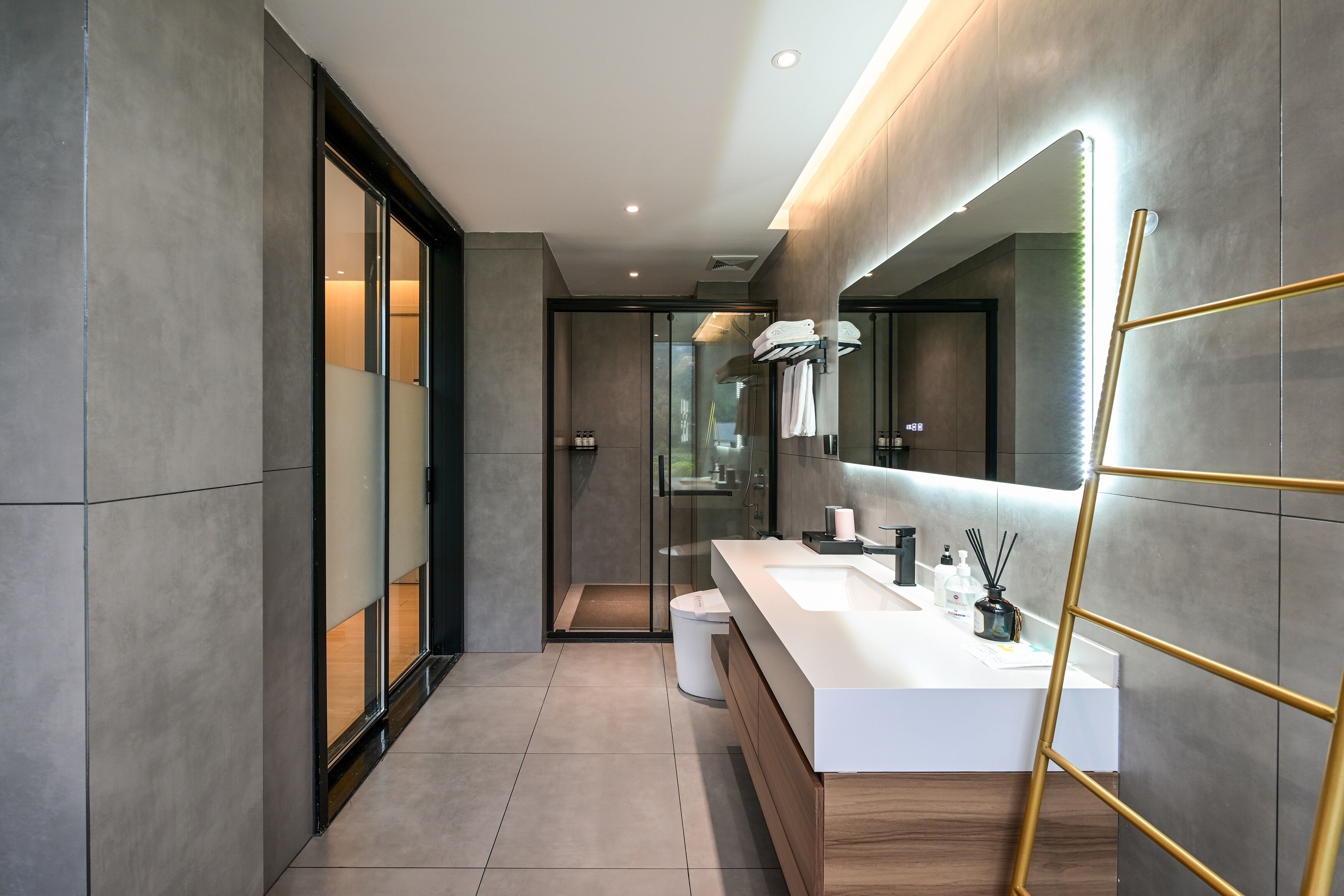 A modern bathroom with a large mirror, a white sink, and a shower area.