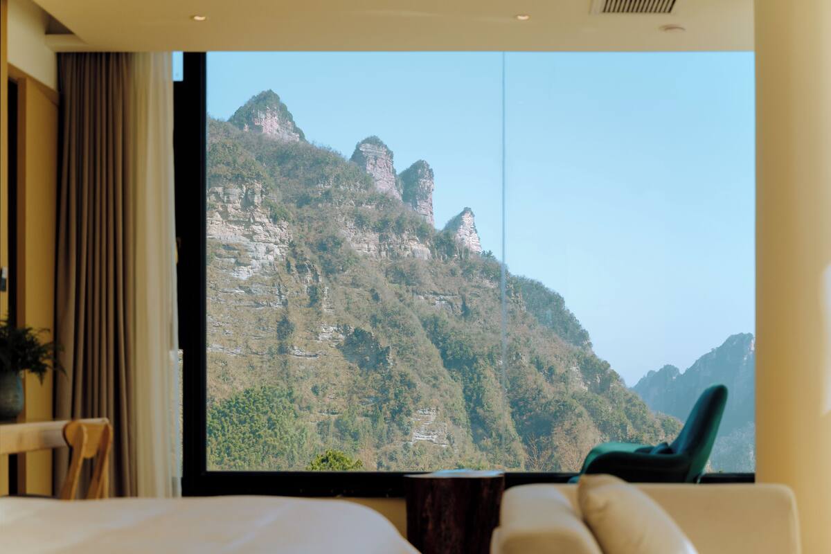 Une chambre d’hôtel dotée d’une grande fenêtre donnant sur un paysage montagneux.