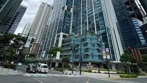 A modern high-rise building with a glass facade, surrounded by other tall buildings. - One Uptown Residence Near St Lukes (Taguig)