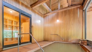 A wooden spa with a hot tub, wooden flooring, and a glass door leading to a covered area. - Goshikionsen Goshikinoyu ryokan (Takayama)