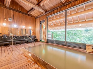 A wooden interior with a hot spring bath, wooden benches, and a large window. - Goshikionsen Goshikinoyu ryokan (Takayama)