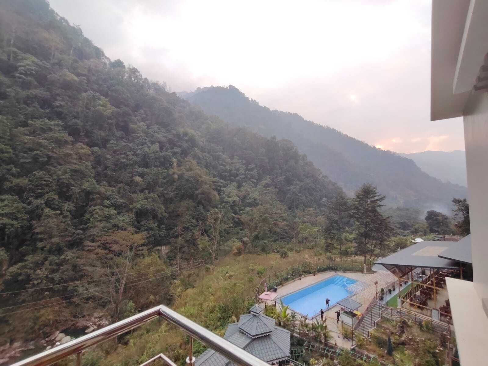 Un hotel con piscina, rodeado de exuberante vegetación y montañas.