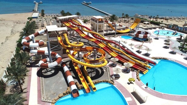 A water park with multiple slides and pools, surrounded by beach chairs and umbrellas. - Nubia real estate aqua beach (Hurghada)