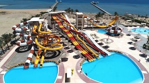 Ein Wasserpark mit zahlreichen Rutschen und Pools, umgeben von Strand und Meerblick.